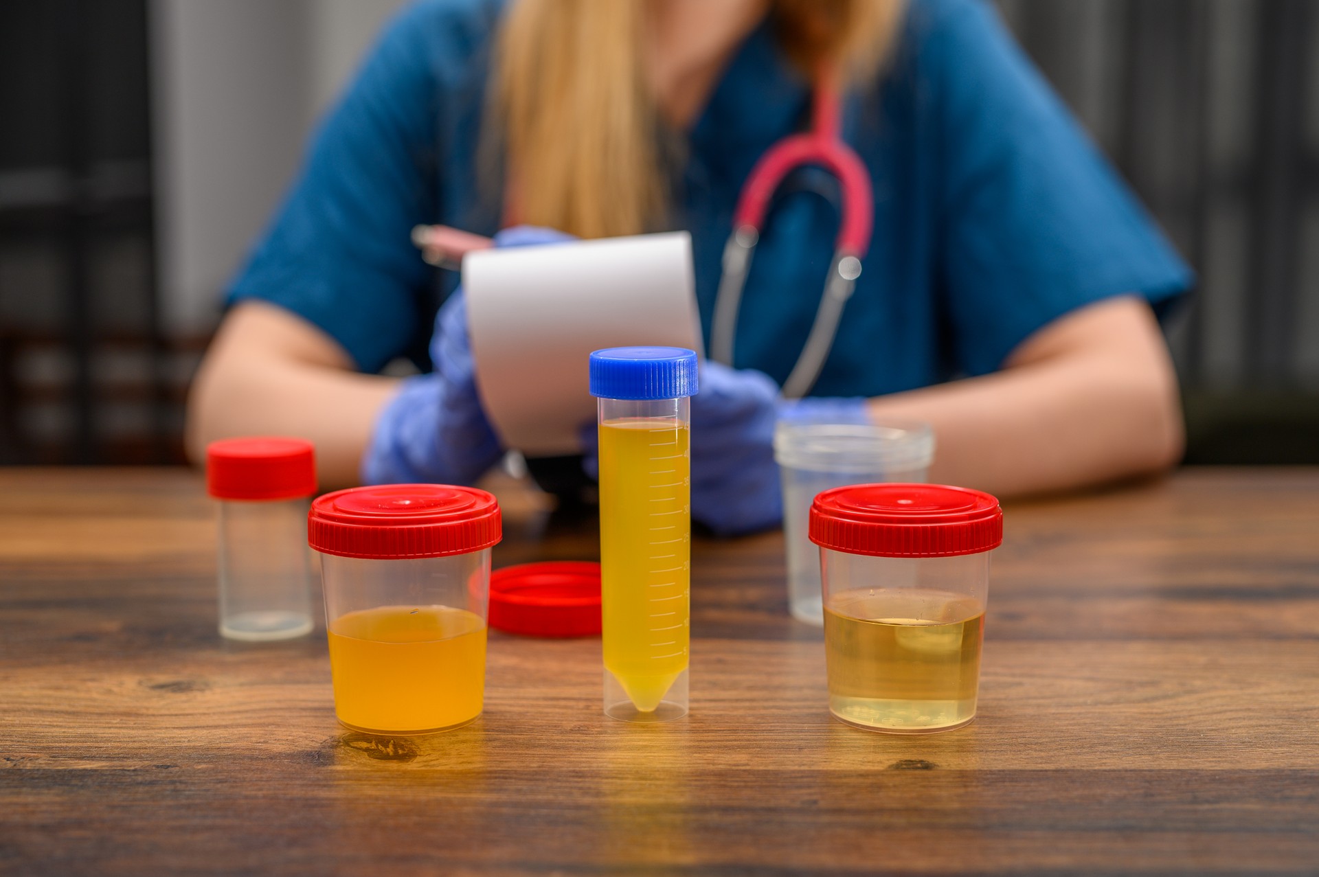 Clinical examination, doctor sits at a desk surrounded by samples in plastic containers and takes notes